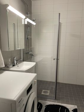 Vaalea kylpyhuone kirkkaalla suihkuseinällä