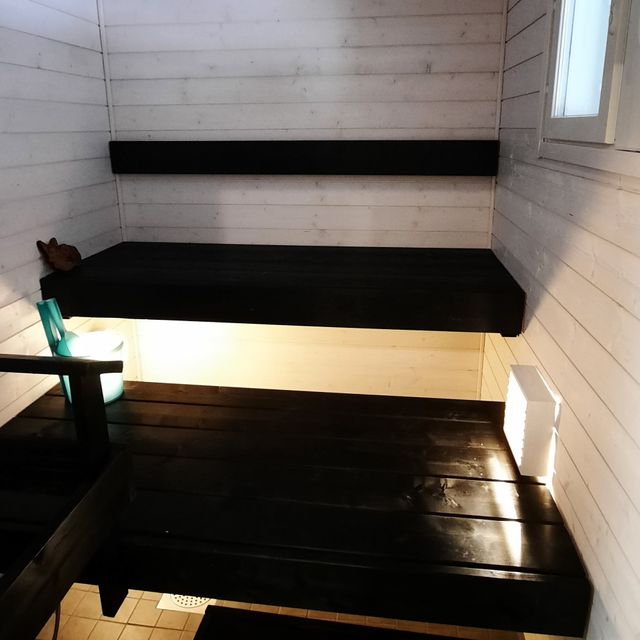 Sauna vaaleilla seinillä ja mustilla lauteilla